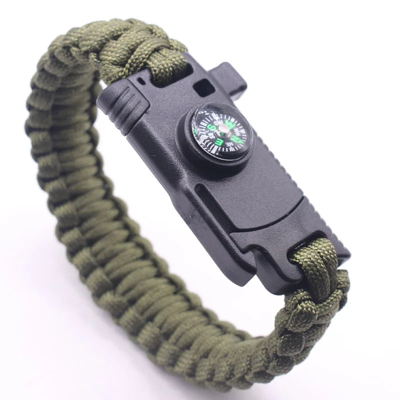 Pulseira de paracord com lâmina, bússola e pederneira da loja arranca toco, ideal para uso tático e aventuras ao ar livre. O design transado das cordas entrelaçadas é destacado em fotografia com fundo branco e iluminação suave, revelando os compartimentos funcionais. A bússola possui roseta verde fluorescente, e a pederneira é discretamente integrado, unindo estilo, praticidade e funcionalidade em um único acessório.