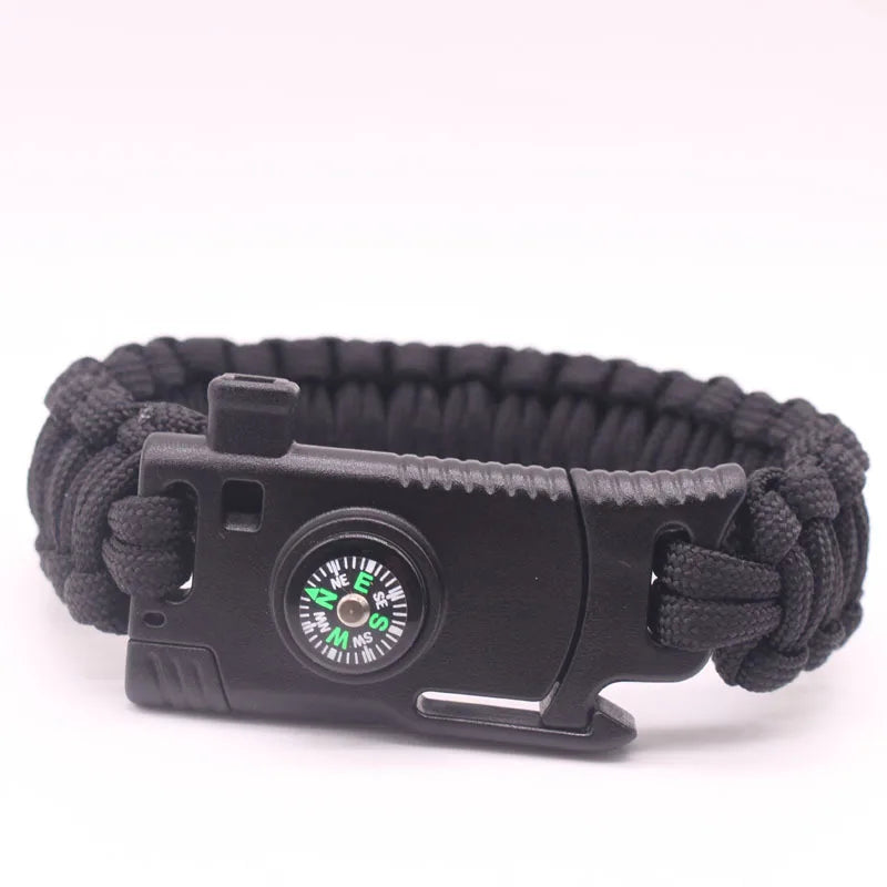 Pulseira de paracord com lâmina, bússola e pederneira da loja arranca toco, ideal para uso tático e aventuras ao ar livre. O design transado das cordas entrelaçadas é destacado em fotografia com fundo branco e iluminação suave, revelando os compartimentos funcionais. esta construída em paracord preto, bússola possui roseta verde fluorescente, e a pederneira é discretamente integrado, unindo estilo, praticidade e funcionalidade em um único acessório.